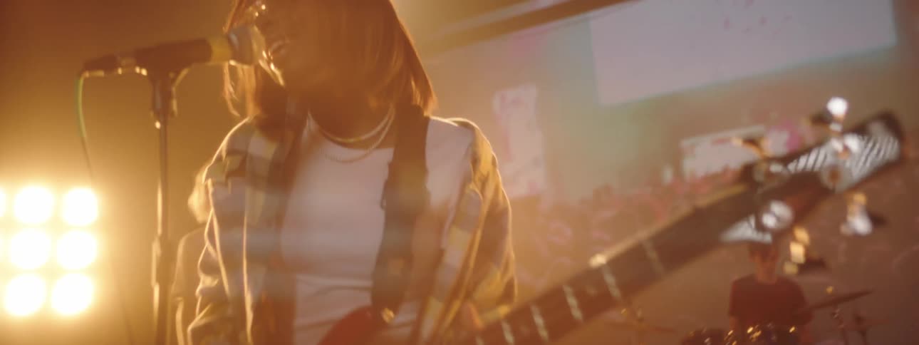 A large band performs together on brightly lit stage