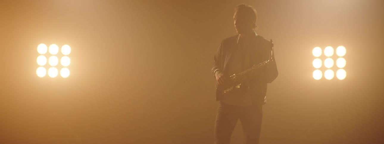 Musician playing the saxophone on a smoky stage in front of pusling lights