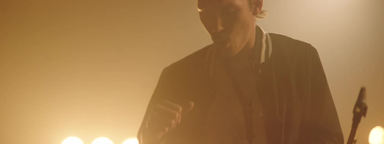 A man dances and sways as he plays the sax with stage lights glowing