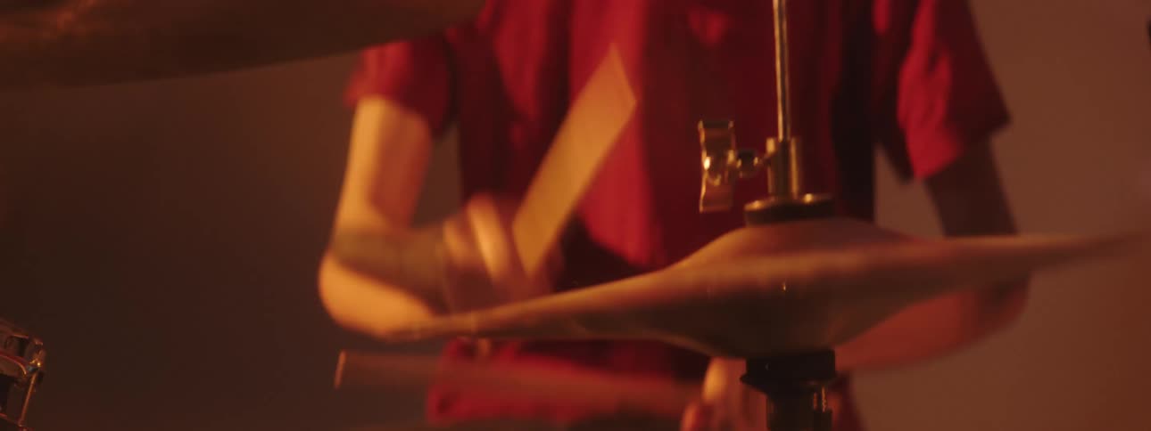 Drummer playing a set of drums on stage under flashing yellow lights
