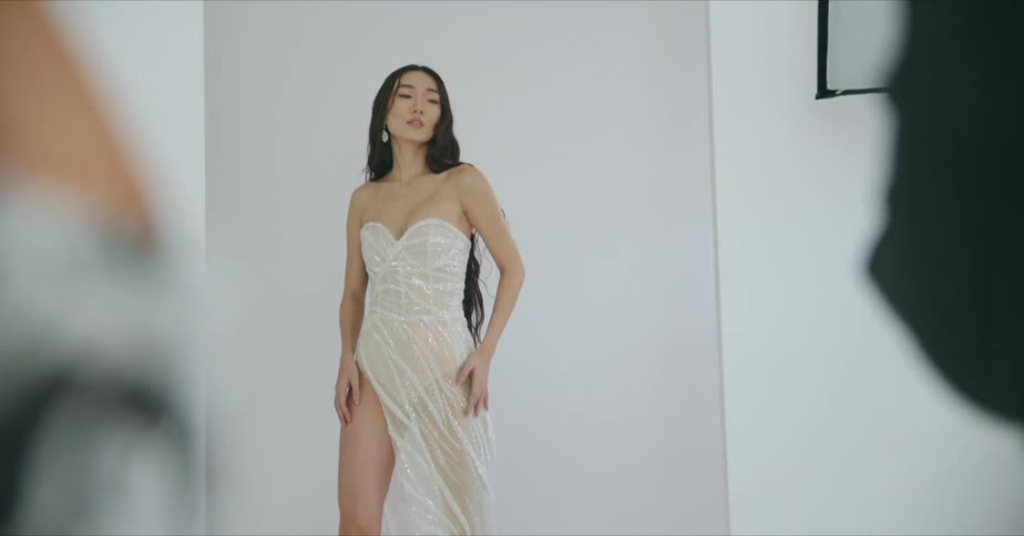 A woman with a dress in a room posing for pictures with a wall in the background