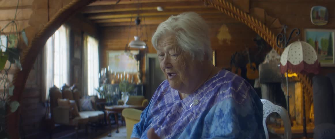 An elderly woman gestures with her hand as she talks seriously to her granddaughter