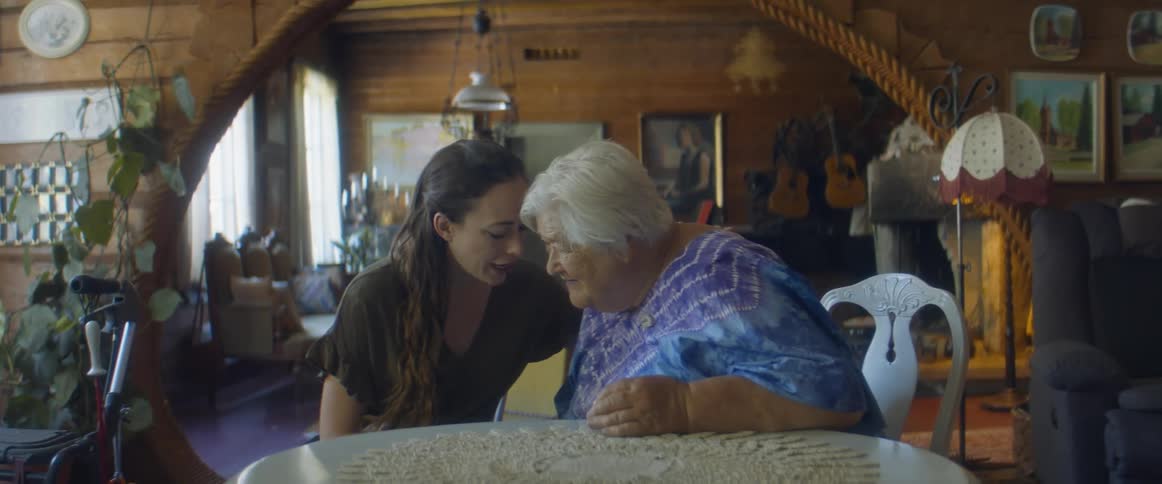 Woman approaches elderly woman to talk with in the living room