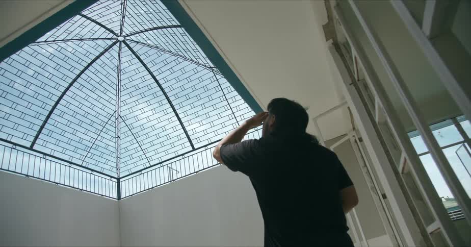 A man in a building looking out a skylight