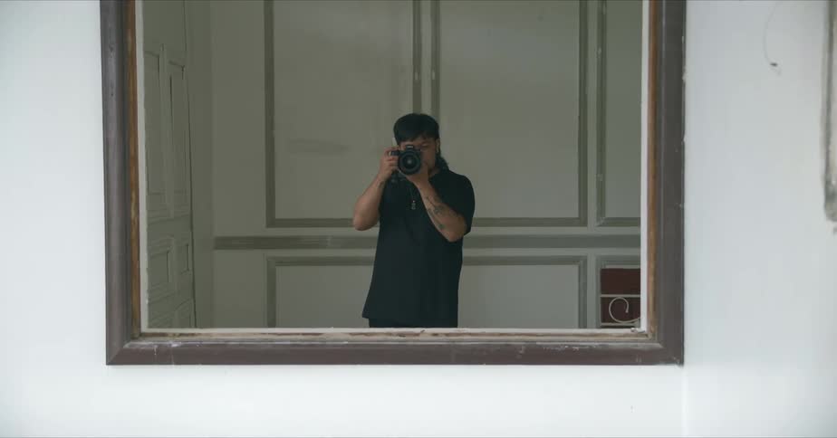Male photographer with beard and long hair taking photo looking in mirror