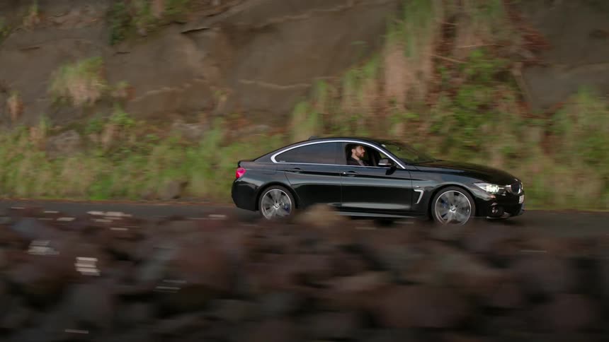 A black car is traveling on a winding mountain road