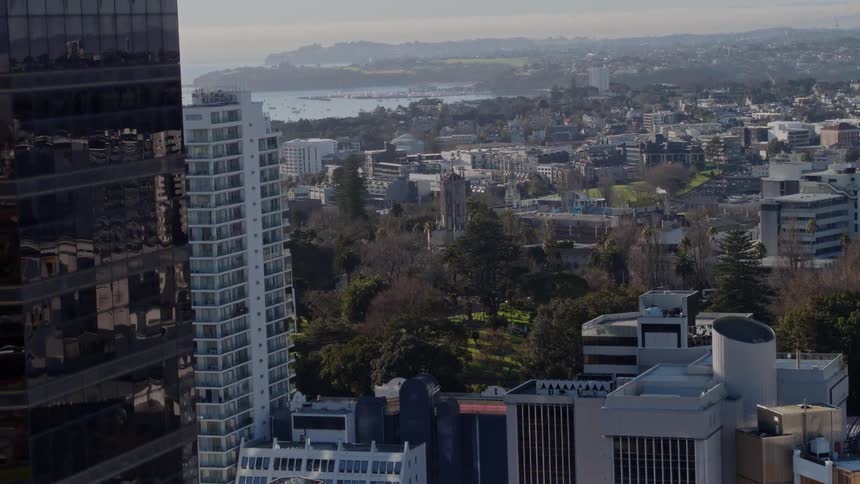 Buildings and trees in the city near the lake as mountains sit in the distance
