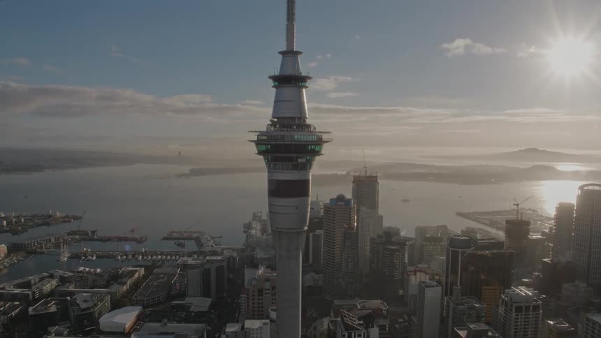 A tall spire building sits in the center of a downtown city along the coast