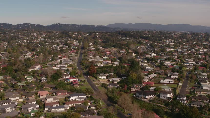 Town stretches to misty hills and forest on the horizon under cloudy sky
