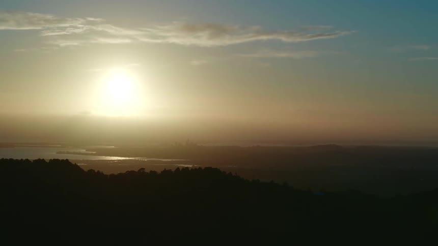 The sun is setting over a mountain coastal area