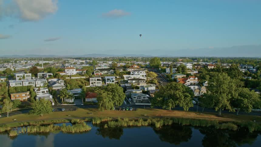 Hot air balloon hovers over the houses in the city near the lake