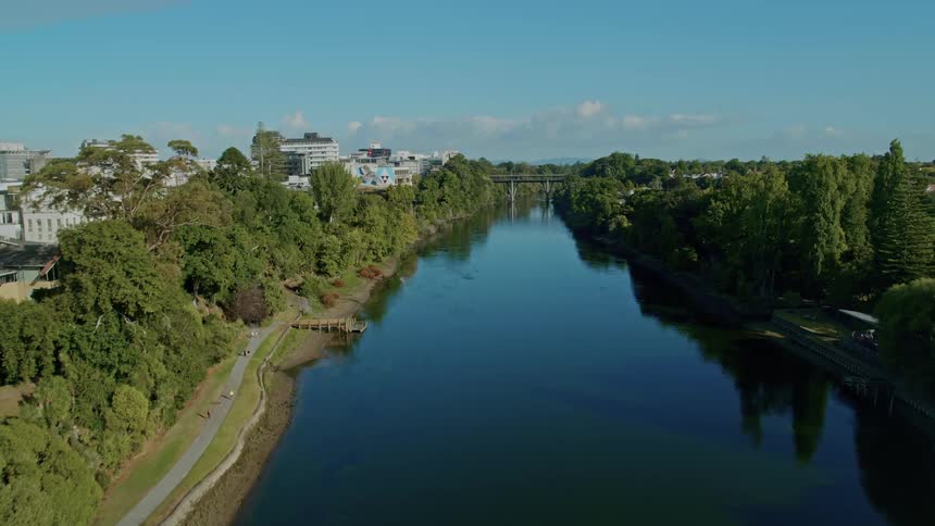 A city skyline with a river and a bridge with the sky and clouds in the background
