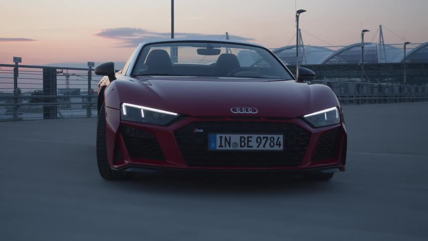 A sports car parked on a boardwalk on the coast at sunset