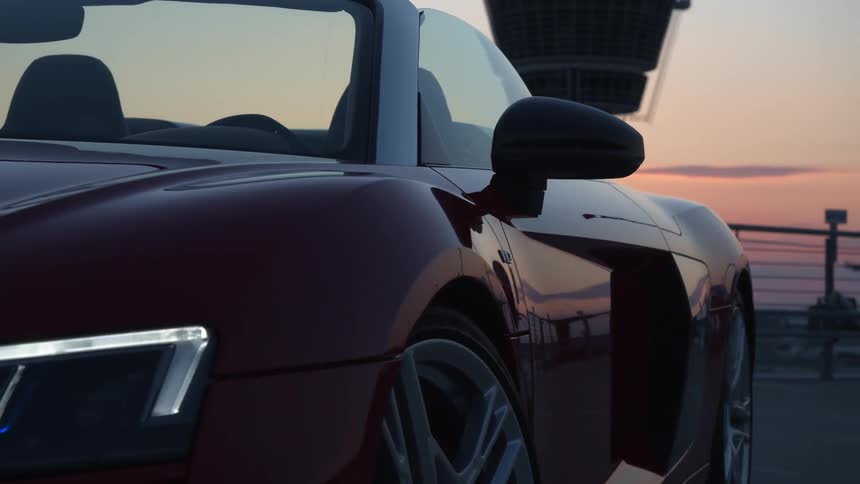 A sports car with headlights with a fence the sky and clouds in the background