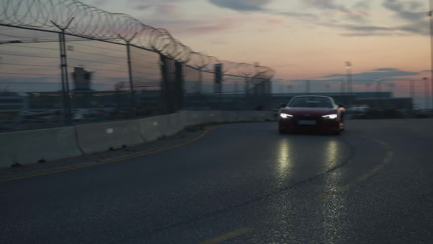 A sports car driving around a track at dusk