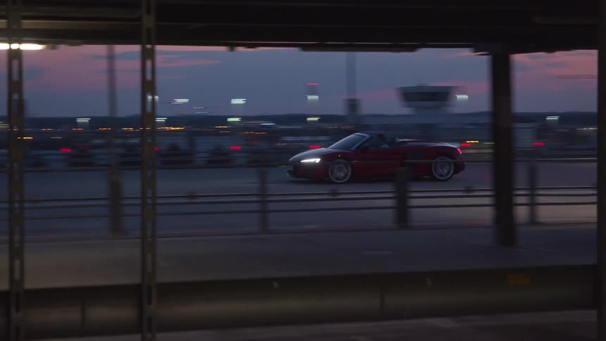 A red convertible comes to a stop on the top floor of an empty parking garage