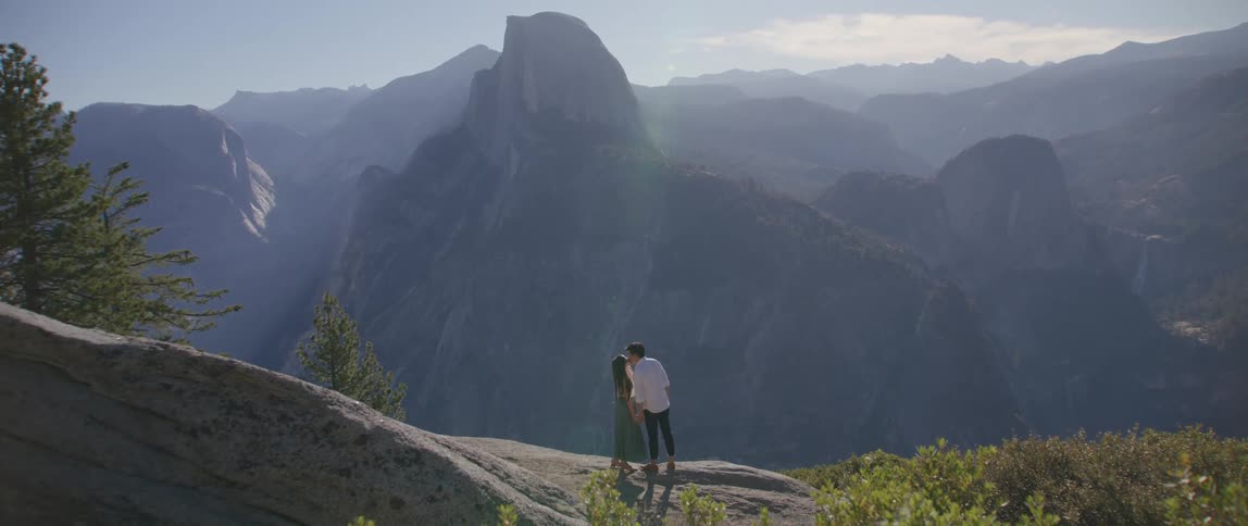 Two people kissing in front of a cliff