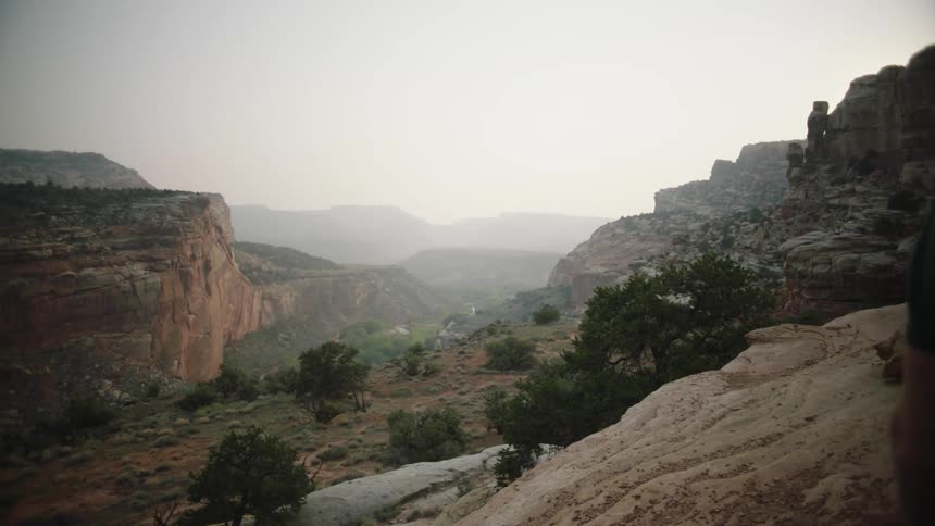 Man and woman sitting on rock watch the horizon with mountains