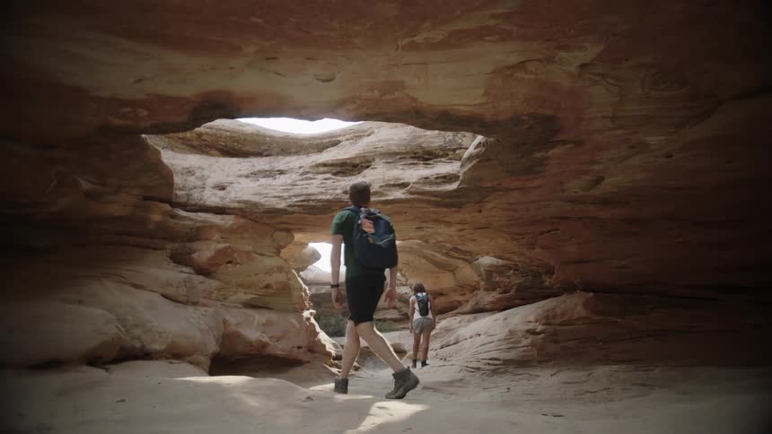 Two people explore a cave with hiking backpacks