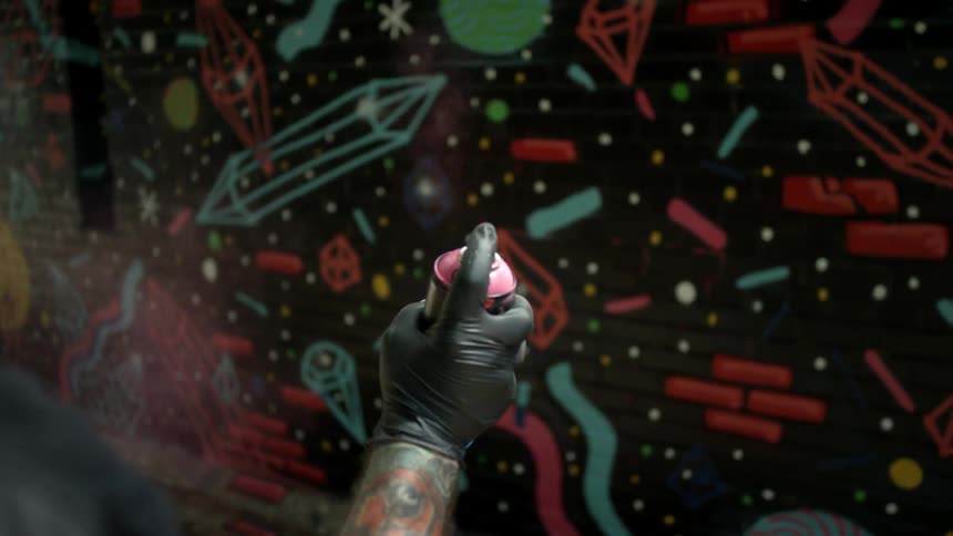 A man sprays pink spray paint in the air