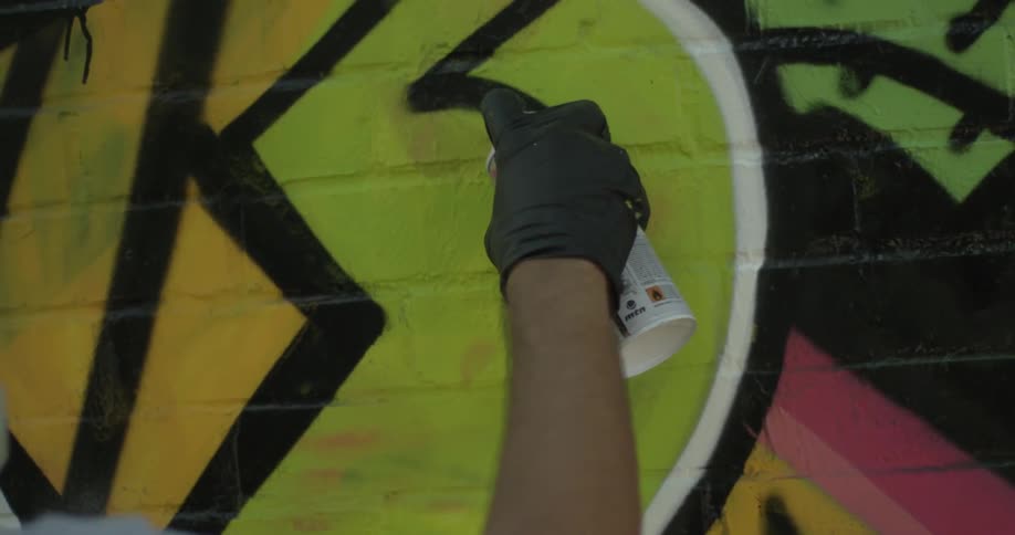 A person spray paints on a wall