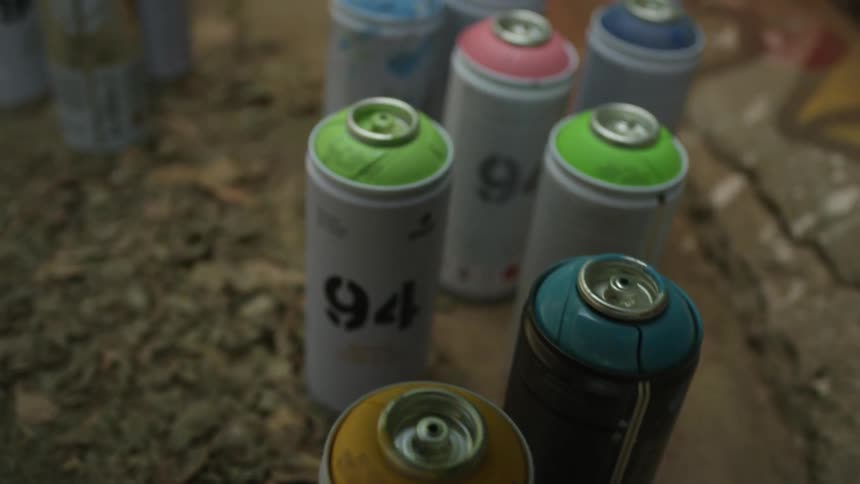 A row of spray paint cans sit on the ground