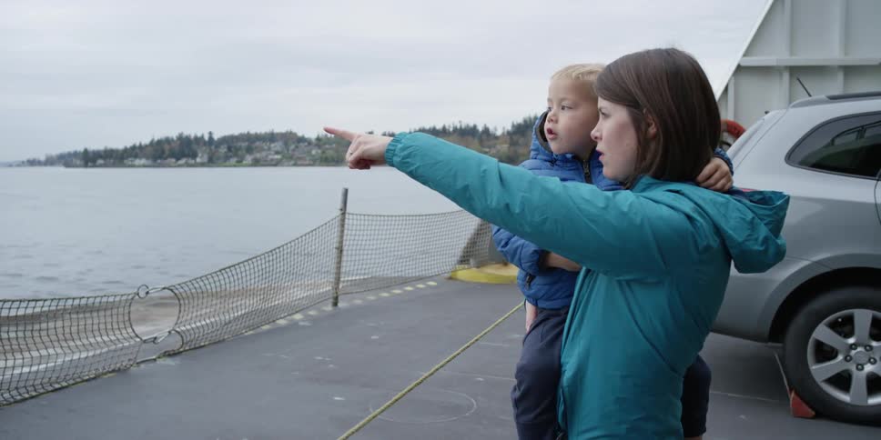 A woman in a blue jacket points something out for her child