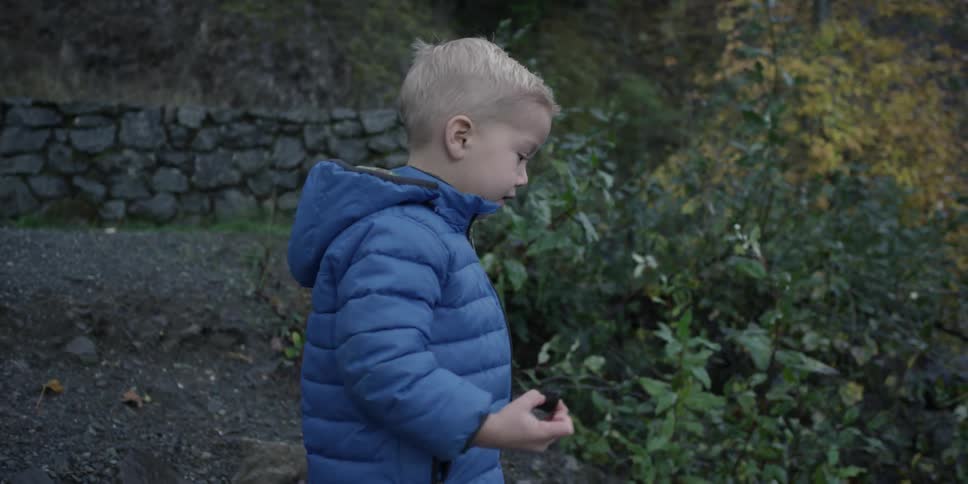 A boy is walking towards the water