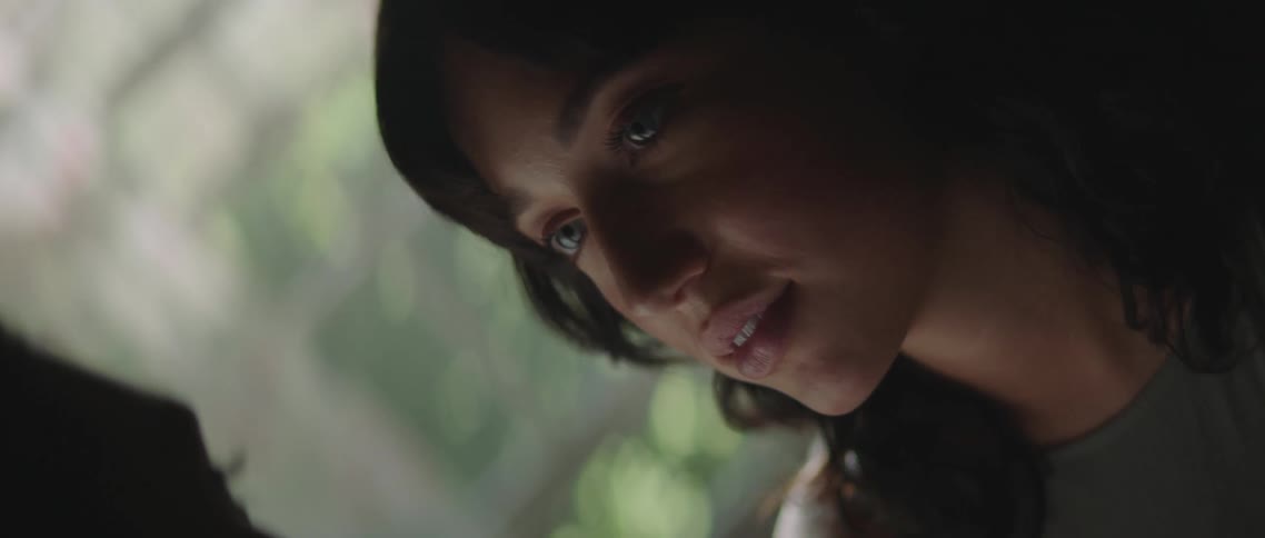 A man and a woman in a room staring at each other with a window and trees in the background