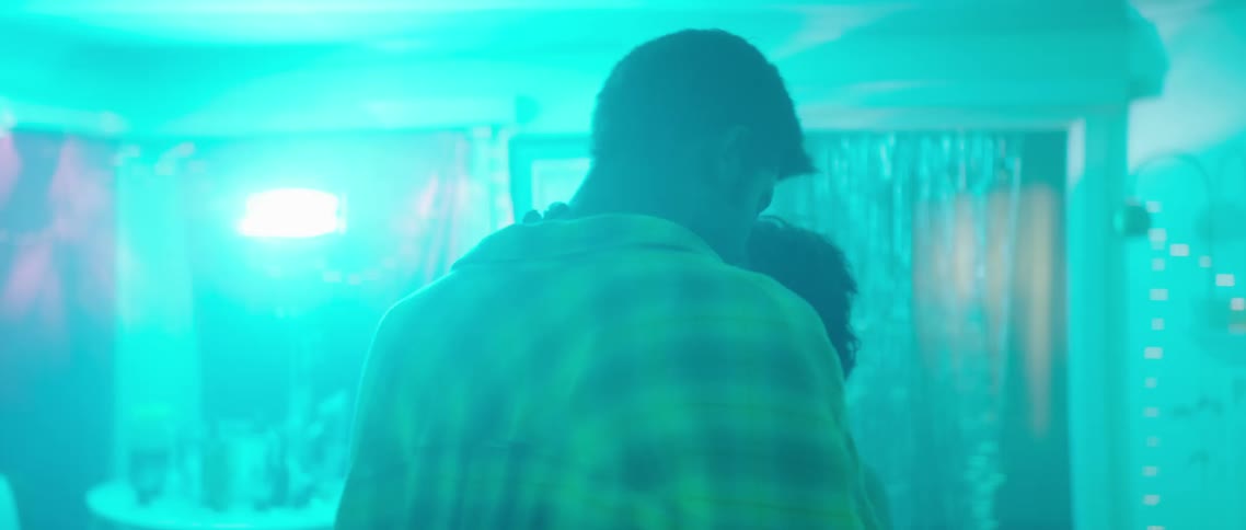 A young man and woman stand close as they dance indoors at a house party