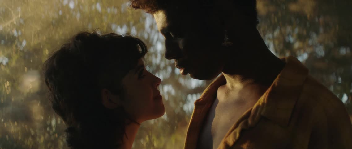A man and woman are smiling at each other as they seem to be dancing slowly