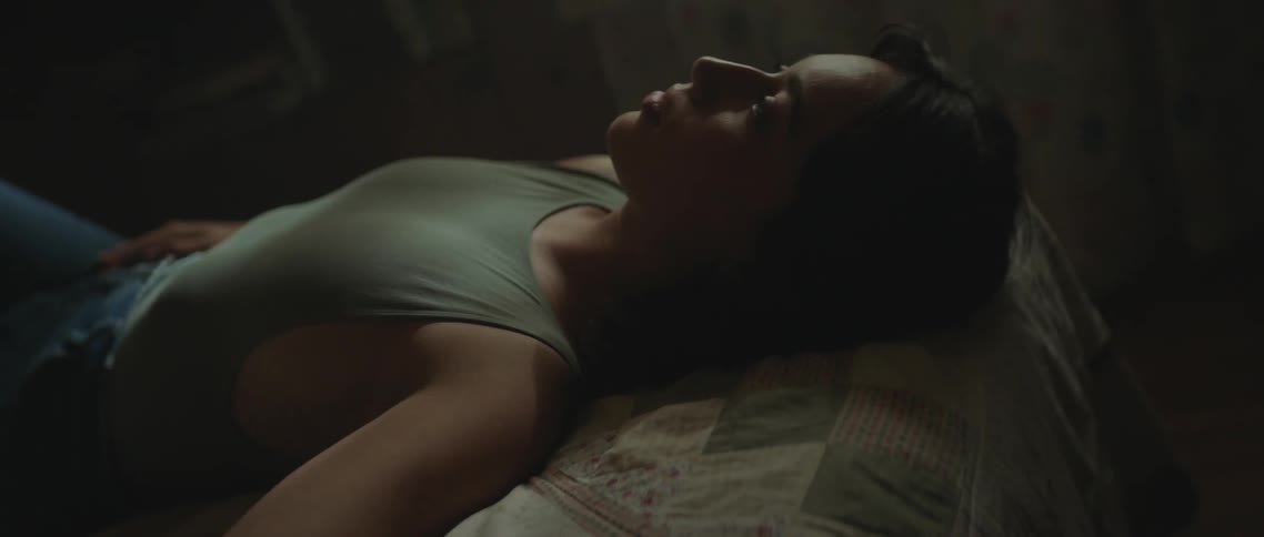 A woman is lying on a bed as the camera moves around her