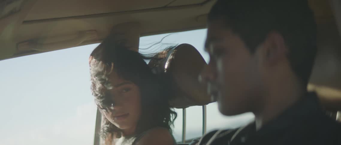 A man is driving a car while a woman sitting next looks at him
