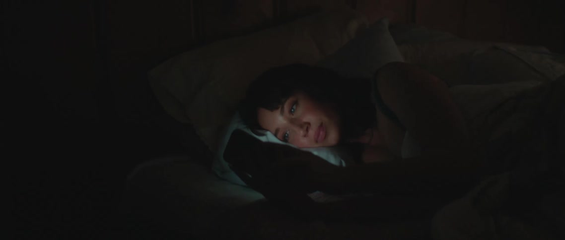 Two people laying in beds using phones