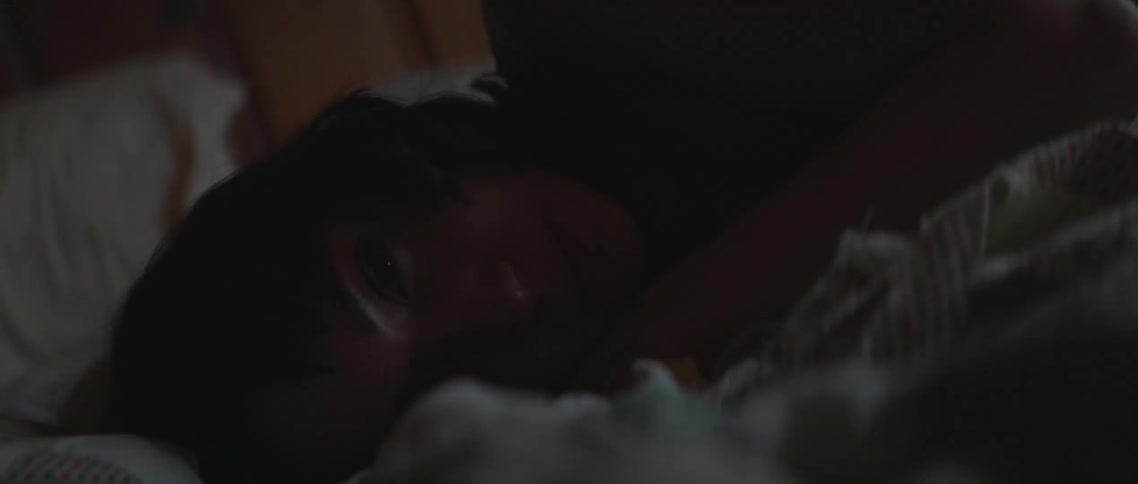 A woman opens her eyes in bed
