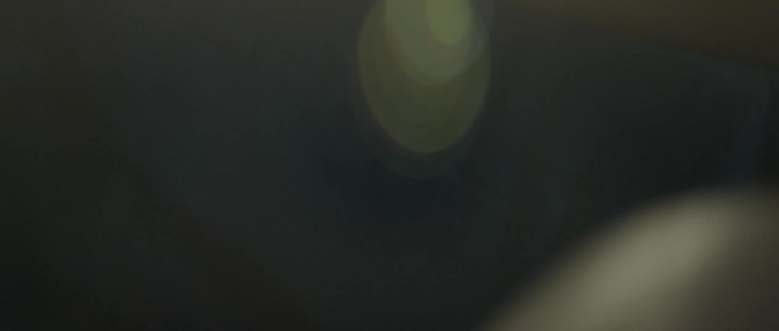 The camera drifts in and out of focus while a bright light shines upon a person beneath it