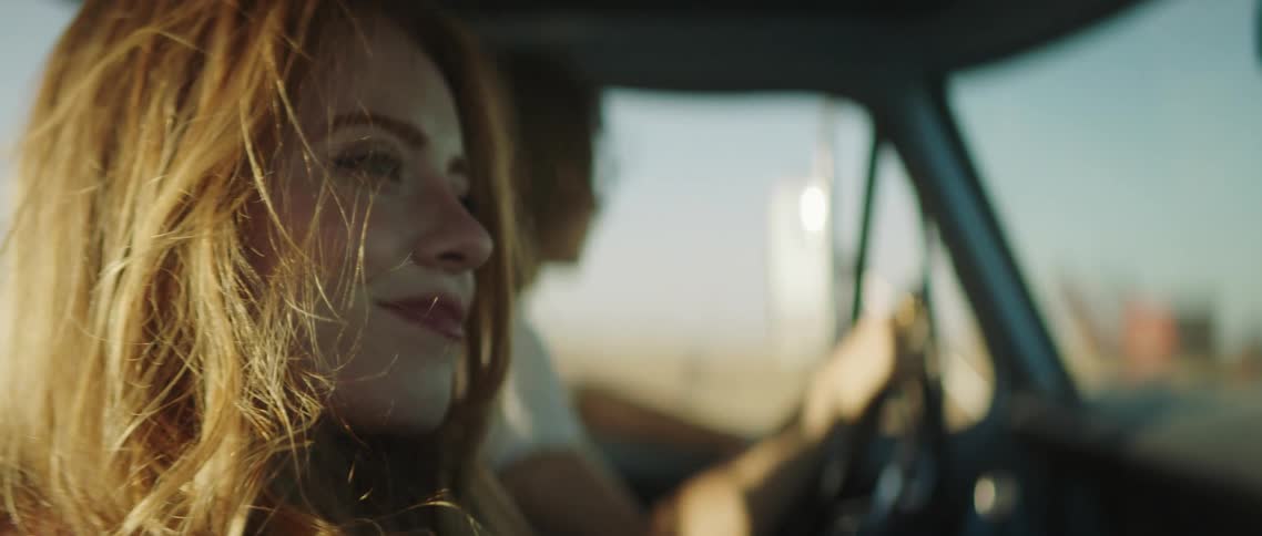 A man and woman driving in a truck down a road