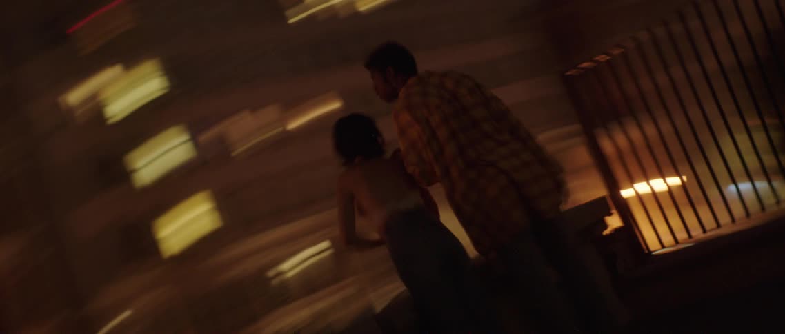 A man and woman standing outside in a city at night