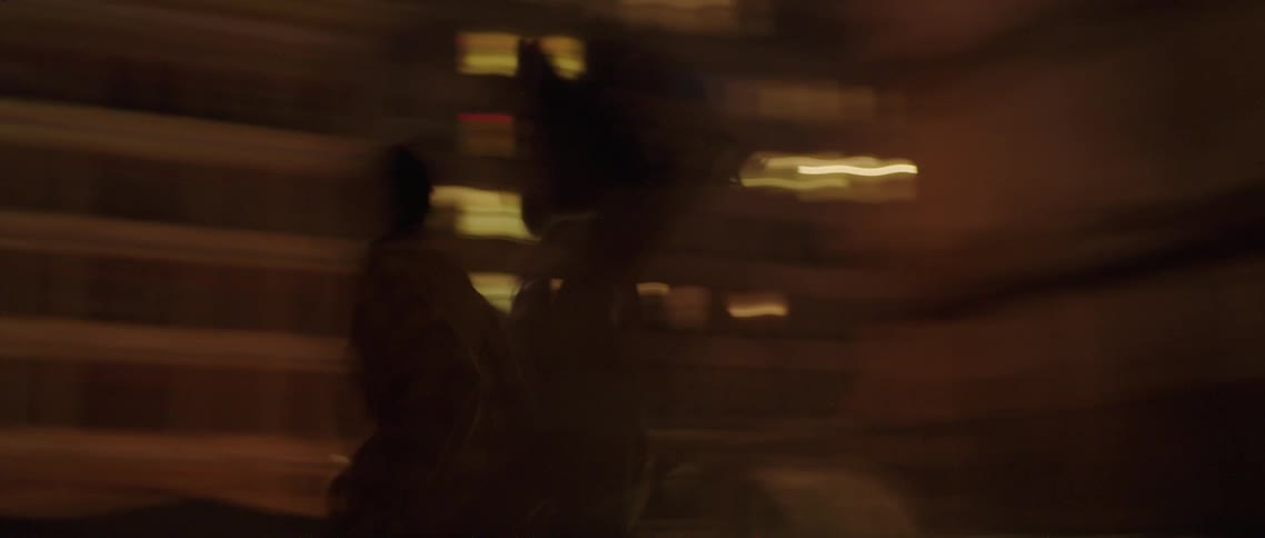 Young couple holding hands running on the rooftop of a building in the city at night