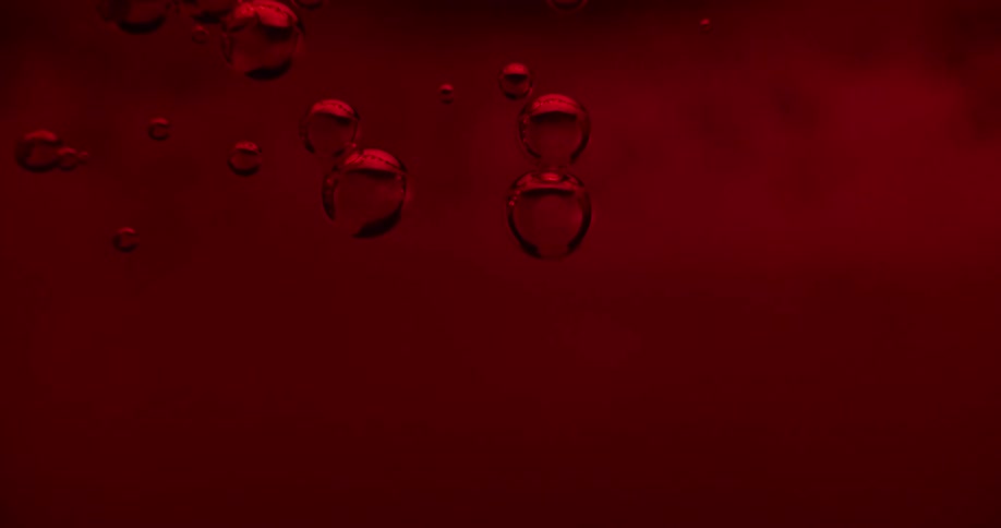 Air bubbles inside a glass tank full of liquid under red lights