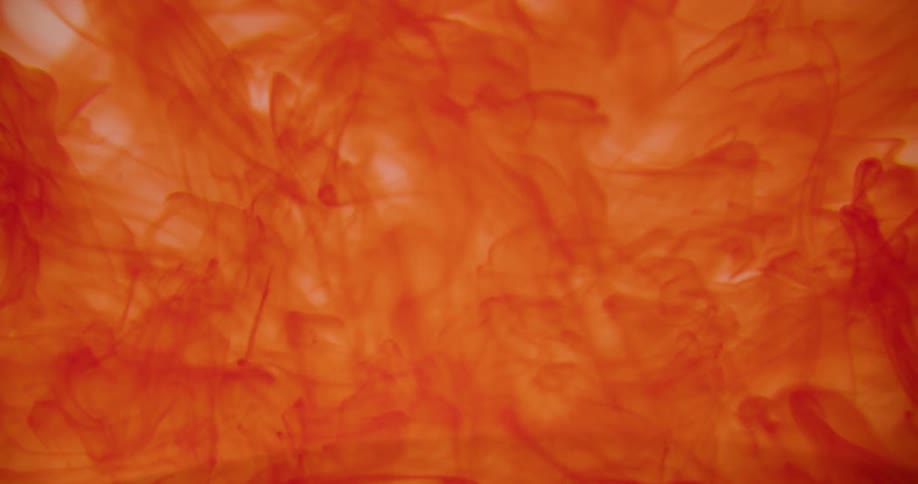 An orange dye rises and mixes in clear liquid
