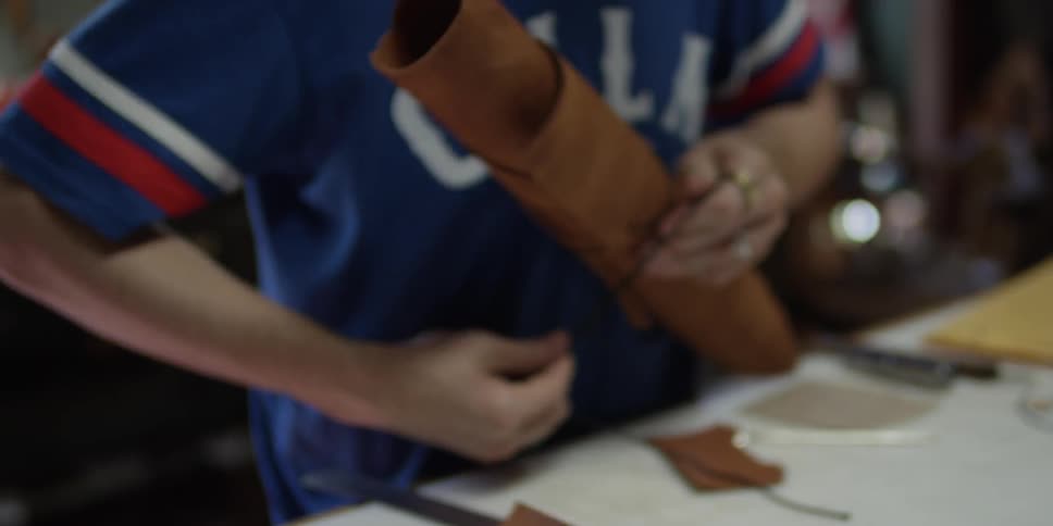 A man wrapping twine around rolled up leather