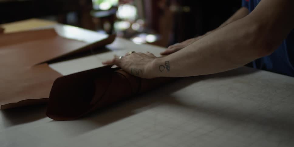 An artisan rolls up leather material