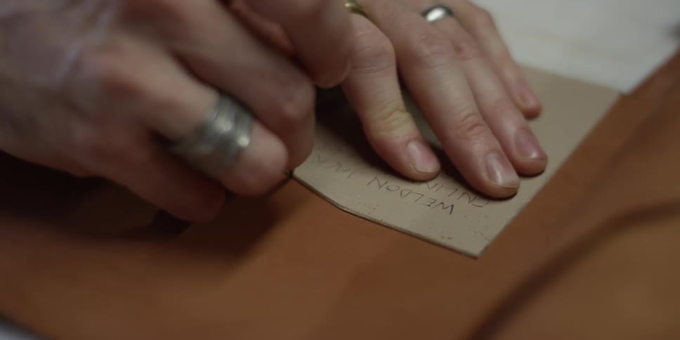 A man uses a tool to cut leather