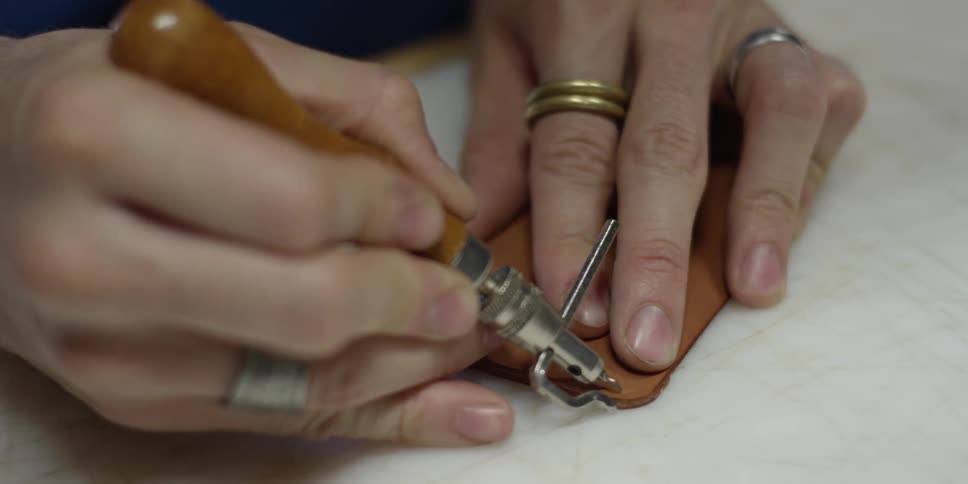 A person cuts a small piece of leather