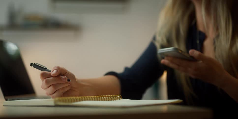 A woman talking on a phone and writing