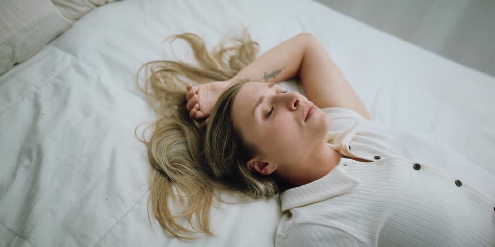 A sad woman thinking while lying down in bed