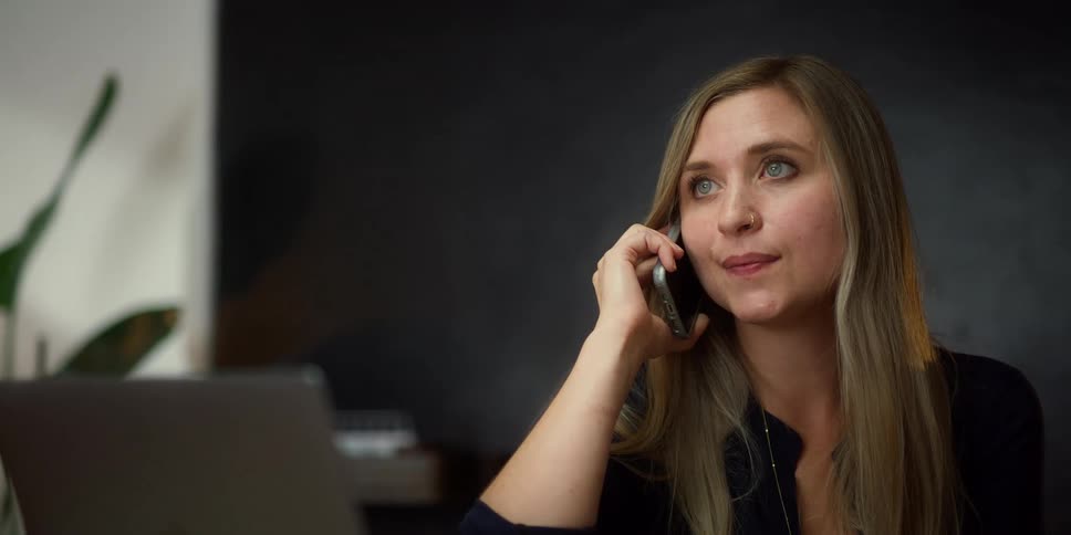 A woman talking on a phone while sitting in an office setting