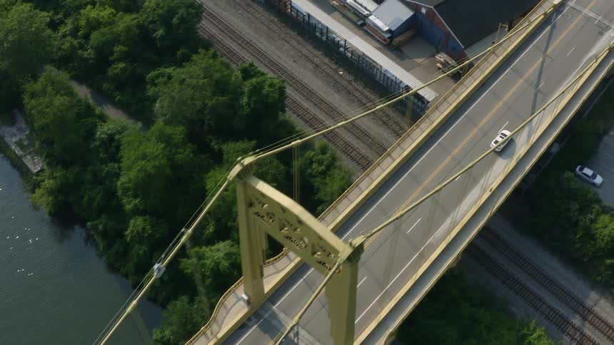 Aerial view of white car crossing the bridge in the city