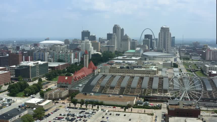 A city skyline with buildings and skyscrapers streets and a ferris wheel with the sky and clouds in the background